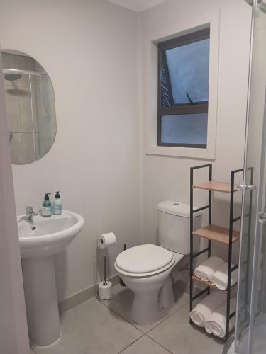 a white bathroom with a toilet and a sink at Cozy Kosmos in Hartbeespoort
