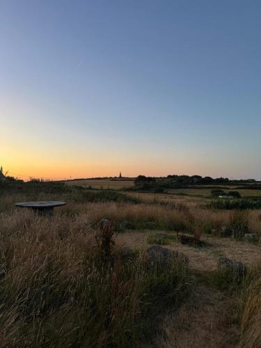 a bench in a field with the sunset in the background at Quiet peaceful relaxing off grid Campervan Seaview and Ponies in Carbis Bay