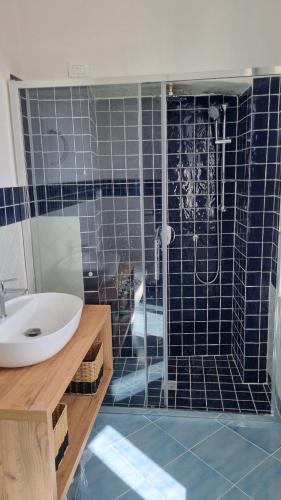 a bathroom with a sink and a shower with blue tiles at Brezza di Terra in Santa Marina Salina