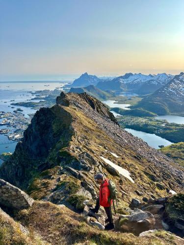 a person with a backpack on top of a mountain at Mountain and Sea View Svolvær in Svolvær