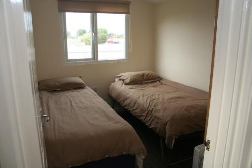 two beds in a small room with a window at Castaway Cabin in St Merryn