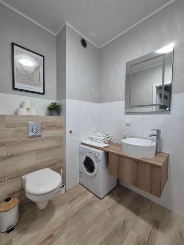 a bathroom with a sink and a washing machine at Apartament Centrum z darmowym podziemnym parkingiem in Stargard