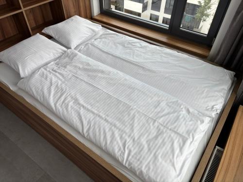 a bed with white sheets and pillows on it at Magnolia Loft Apartments in Wrocław