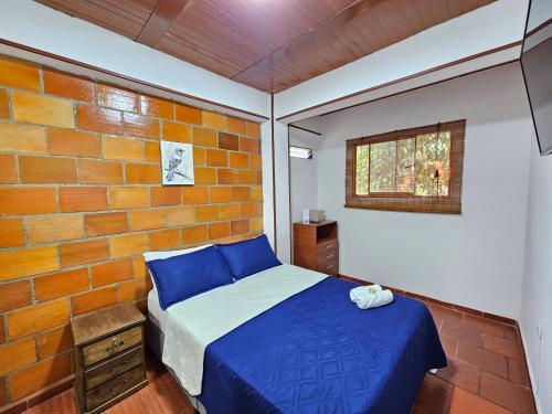 a bedroom with a blue bed and a brick wall at Hotel Finca Recreacional La Fortaleza 
