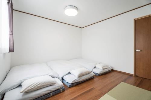 una cama blanca con almohadas en una habitación en Fuji Mason's Villa, en Fujiyoshida