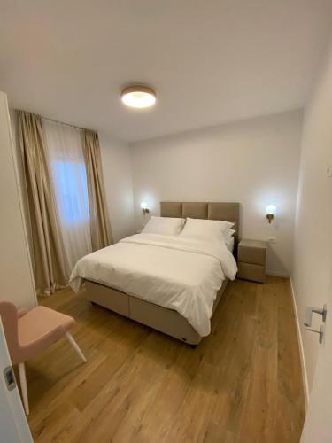 a bedroom with a large white bed and a chair at Vila Sunset in Kaštela