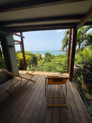 a porch with two chairs and a view of the ocean at Le lodge des raisiniers in La Trinité