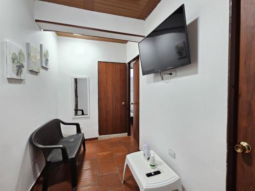 a living room with a chair and a tv on the wall at Hotel Finca Recreacional La Fortaleza 