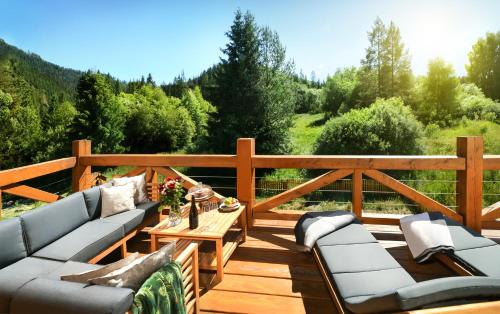 a wooden deck with couches and a coffee table at Chalet Oasis - Luxury 5-Bedroom Chalet with Panoramic Views in Huty