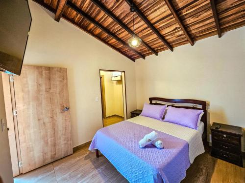 a bedroom with a bed with purple pillows at Hotel Finca Recreacional La Fortaleza 