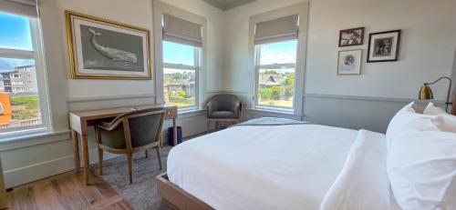 a bedroom with a bed and a desk and windows at Hotel Sylvia in Newport