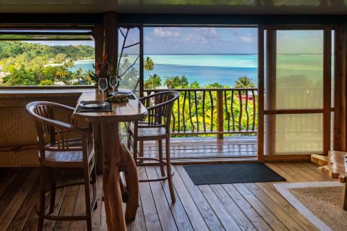a room with a table and chairs and a view of the ocean at Fare Matira Hau in Bora Bora