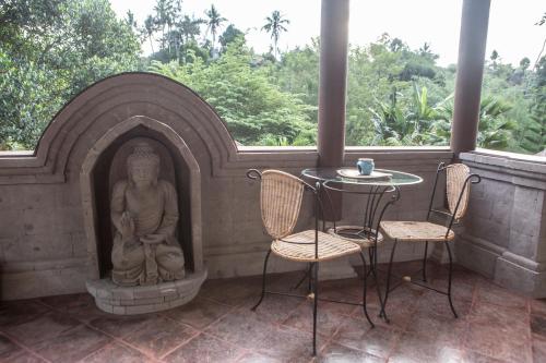 a patio with a statue and a table and chairs at Avalon Ubud Castle & SPA in Ubud