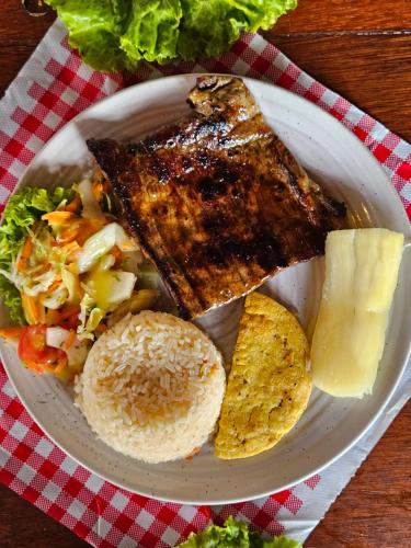 a plate of food with meat and a salad and chips at Hotel Finca Recreacional La Fortaleza 