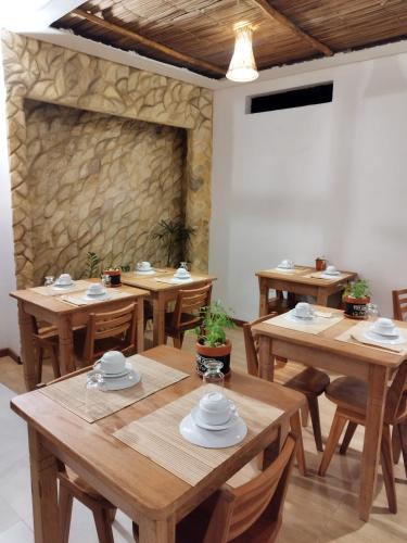 a dining room with wooden tables and a stone wall at Japaratinga Suites in Japaratinga