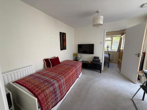 a bedroom with a large bed with a red blanket at Cosy Apartment with Private Access and Kitchenette in Guildford in Worplesdon