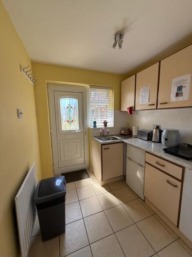 a kitchen with a sink and a window and a door at Cosy Apartment with Private Access and Kitchenette in Guildford in Worplesdon
