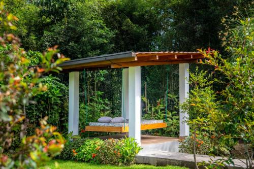 a gazebo with a bench in a garden at Royal River Suites & Spa Aparthotel in Mindo