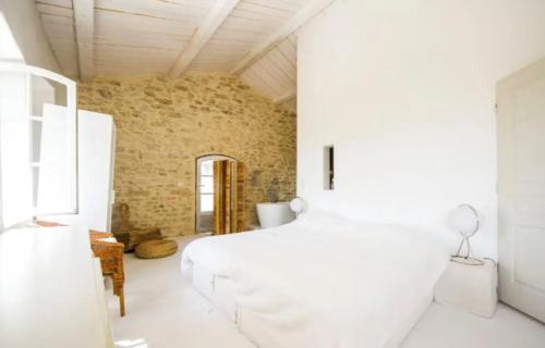 une chambre avec un lit blanc et un mur de briques dans l'établissement Maison d exception au coeur de Goult avec piscine privée et vue panoramique, à Goult