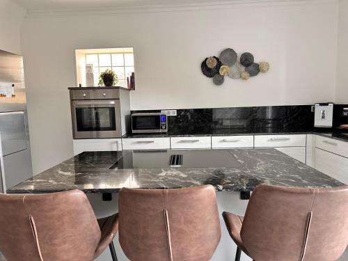 a kitchen with a marble counter top and chairs at 80qm Luxus Apartment mit großer Terrasse in Saarbrücken