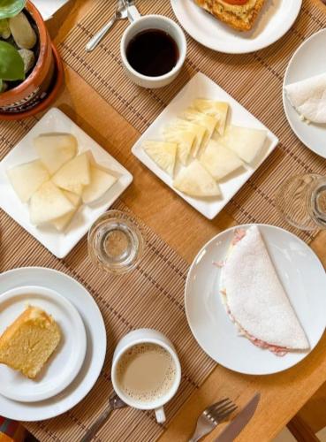 a table with plates of food and cups of coffee at Japaratinga Suites in Japaratinga
