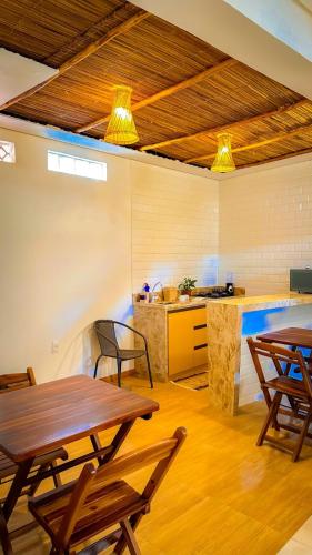 a room with tables and a kitchen with a counter at Japaratinga Suites in Japaratinga