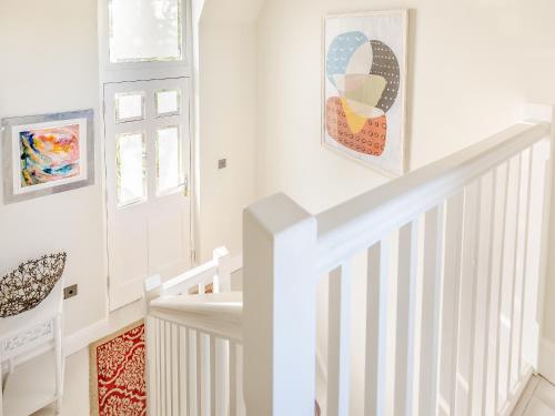 a white staircase in a home with art on the wall at Hallmark Lodge in Tenterden