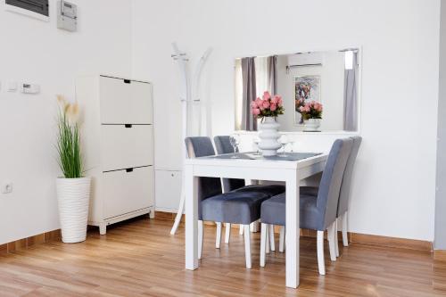 a dining room with a white table and blue chairs at Apartman Aki in Bele Vode
