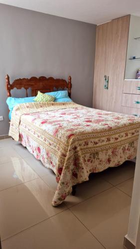 a bedroom with a bed with a floral bedspread at Departamento Familiar en primer piso in Trujillo