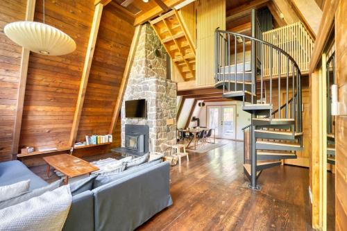 a living room with a stone fireplace and a staircase at Modern A-Frame Cabin in the Woods in Rhododendron