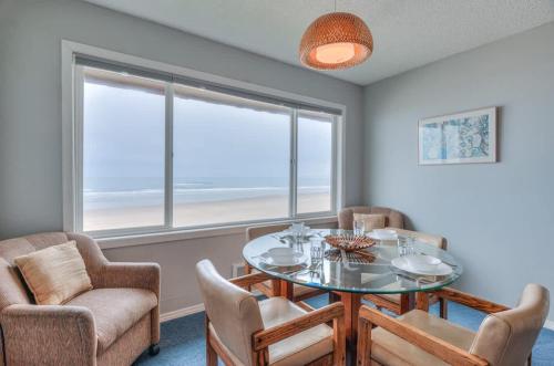 a dining room with a table and chairs and a window at Beachy Second Floor Beachfront Suite With Full Kitchen - Sleeps 4 - Pool and Sauna in Lincoln City