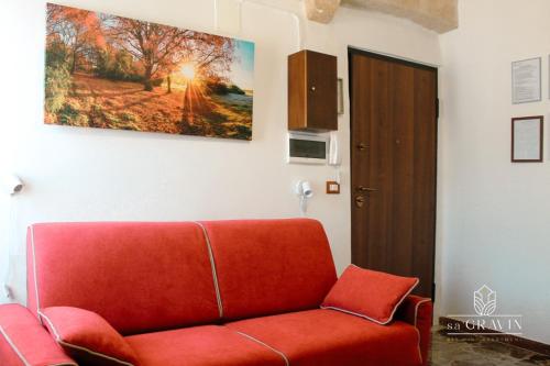 a red couch in a living room with a painting on the wall at B&B sa' GRAVIN in Castellaneta