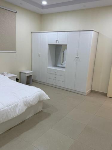 a white bedroom with a bed and a cabinet at شقة خالد المفروشة in Quai