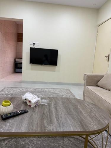 a living room with a table and a couch and a television at شقة خالد المفروشة in Quai