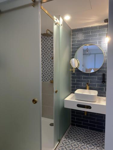 a bathroom with a sink and a shower with a mirror at Na Crista da Onda in Nazaré