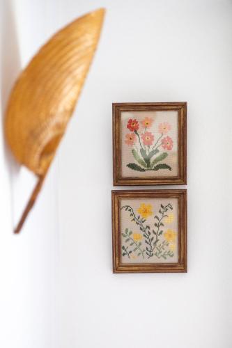 two framed pictures of flowers on a wall with a knife at Retiro das Buganvílias in Sesimbra