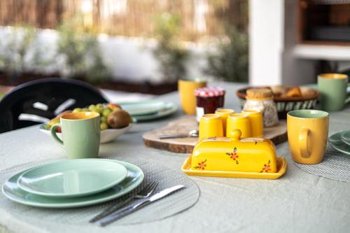 a table with plates and cups and a yellow box on it at Retiro das Buganvílias in Sesimbra