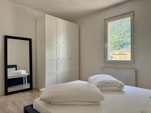 a white bedroom with two beds and a mirror at 1Dest - The Roman Spot in Riva del Garda