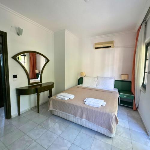 a bedroom with a bed and a chair and a mirror at Club Mel Holiday in Ortaca