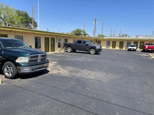 a parking lot with two trucks parked in front of a building at Delux Inn in Big Spring