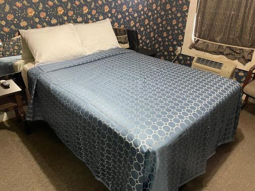 a bed in a room with a blue comforter at Delux Inn in Big Spring