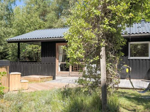 a black house with a porch and a wooden deck at 6 person holiday home in Brovst-By Traum in Brovst