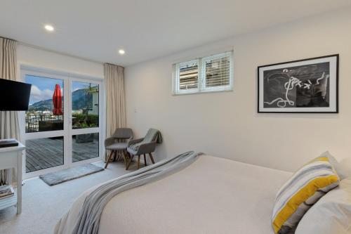 a white bedroom with a bed and a window at Queenstown House Bed & Breakfast and Apartments in Queenstown