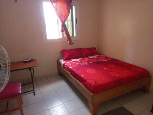 a bedroom with a red bed and a window at Fèmi in Rufisque