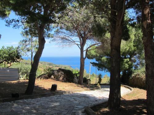 a path through trees with the ocean in the background at Palms Villa in Scopello