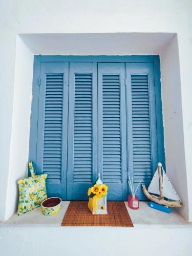a window with blue shutters on a white wall at TriΖin in Galatas