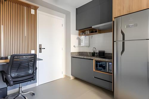 a kitchen with a black chair and a refrigerator at Today Perdizes in Sao Paulo