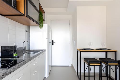 a kitchen with white cabinets and a counter with stools at Today Perdizes in Sao Paulo
