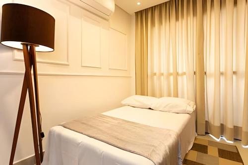 a small bedroom with a bed and a lamp at Today Perdizes in Sao Paulo