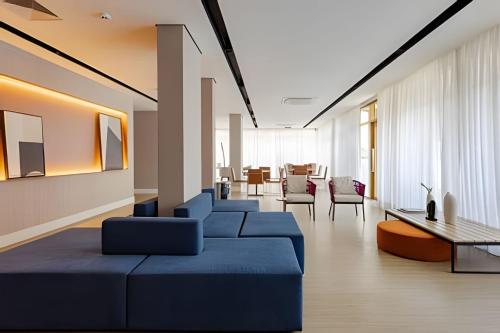 a living room with a blue couch and chairs at Today Perdizes in Sao Paulo